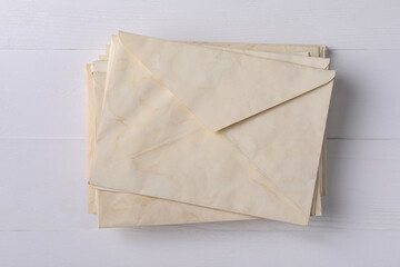 Stack of old letter envelopes on white wooden table, top view