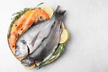 Different fresh sea food with spices in bowl on light grey table, top view. Space for text