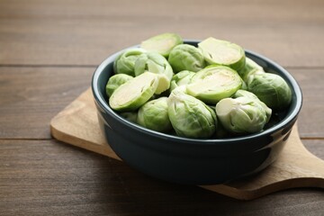 Fresh green Brussels sprouts in bowl on wooden table, closeup
