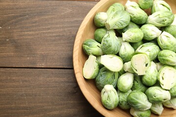 Fresh green Brussels sprouts in bowl on wooden table, top view. Space for text