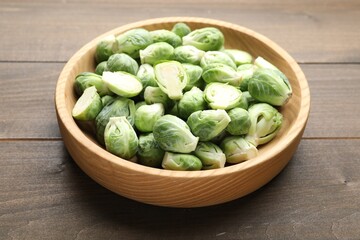 Fresh green Brussels sprouts in bowl on wooden table, closeup