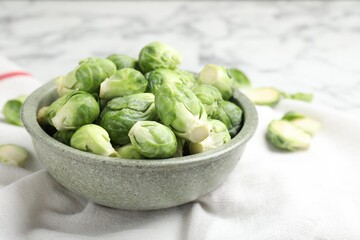 Fresh Brussels sprouts in bowl on white table, closeup