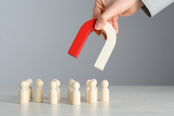 Woman with magnet attracting wooden human figures at light table, closeup