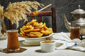 Griwech crunchy pastries , an Algerian dessert made with dough, fried and then coated with syrup and sesame seeds and flying honey spoon 