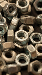 A pile of nuts with a lot of different sizes. The nuts are all silver and have a similar shape