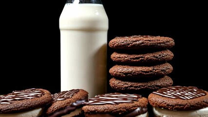 A stack of chocolate cookies sit next to a glass bottle of milk - Powered by Adobe