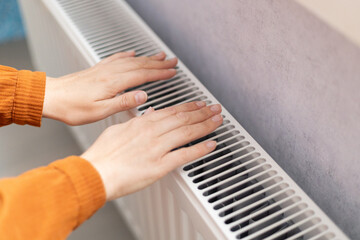 female hands are warming themselves near the radiator