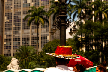 Pessoa com chapéu de cor vermelha andando nas ruas do centro de São Paulo. 