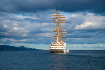Fototapeta premium A view of a sailing ship leaving the harbor in Ponta Delgada in the Azores in summertime