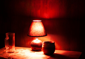 Red lamp and pot on table in dark