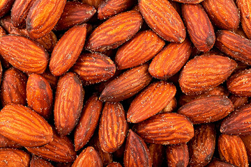 Salted and roasted almond nuts as background, top view.
