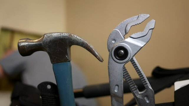 Foreground plumbing tools in toolbox as plumber fixes residential shutoff 
