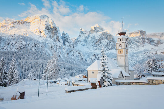 The distinctive church of Colfosco (Kolfuschg) near Corvara with the Sella group Dolomites mountains in the background under a fresh layer of snow in the Alta Badia ski resort in Italy.