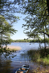 A blue wooden boat moored on the shore of a lake, Borki, Warmian-Masurian Voivodeship, Poland