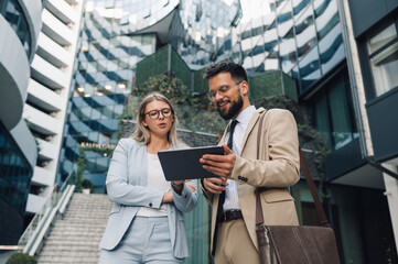 Business people using digital tablet discussing work outside office building