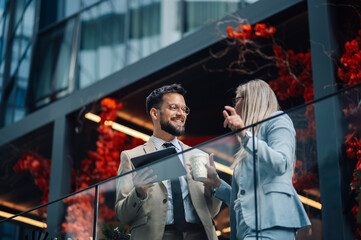 Two business people having a casual meeting on office balcony