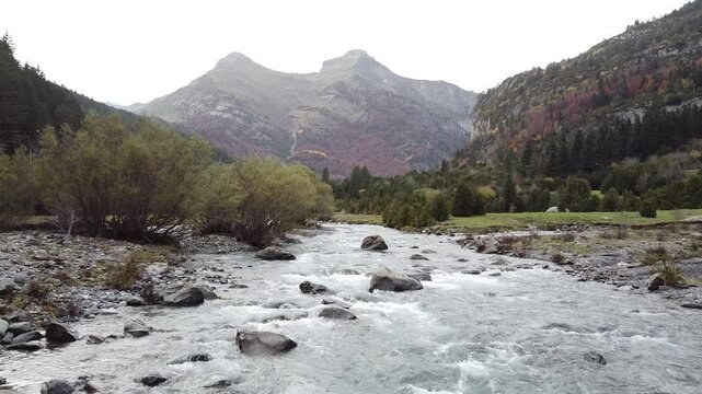 Vuelo de dron a ras del r&iacute;o con paisaje monta&ntilde;oso y excursionistas en el Parque Nacional de Ordesa
