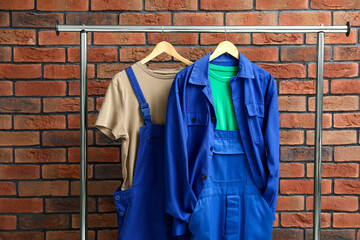 Workers' uniforms on clothing rack near brick wall