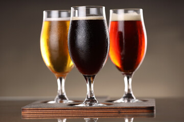 Glasses with different types of beer on mirror surface, closeup