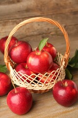 Fresh ripe red apples in wicker basket on wooden table