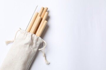 Bamboo drinking straws and cleaning brush in bag on white background, top view. Space for text