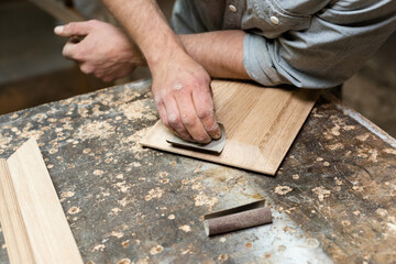 The carpenter grinds the bevels of the panels with sandpaper