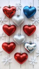 Fototapeta premium A series of heart-shaped Christmas ornaments in red, silver, and blue colors with snowflake designs on a white wooden background