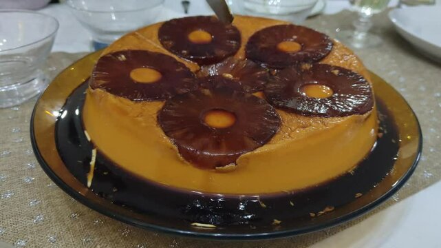 Flan with dancing pineapple about to be cut
