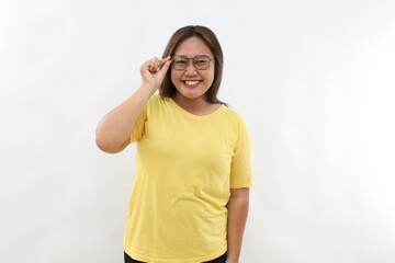 Happy attractive female looks curiously, touches frame of spectacles, concentrated at camera, poses indoor. Human face expressions concept