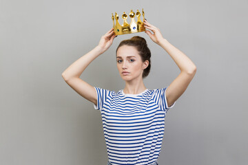 Woman in golden crown looking with arrogance and confidence, privileged status.