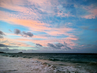 Golden hour clouds above the tranquil ocean waves at dusk on a serene beach
