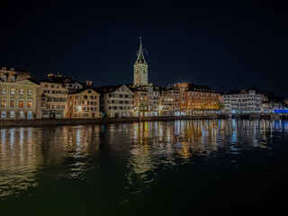 Beautiful aerial view of the city of Zurich in Switzerland at night - the Limmat River and its iconic churches, buildings rivers and Clocks.