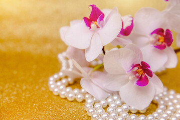 A branch of white orchids on a shiny gold background
