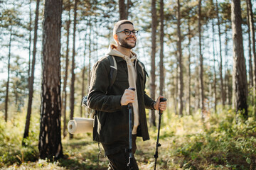 Young caucasian man hiking or trekking through the forest	