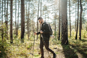 Young caucasian man hiking or trekking through the forest	