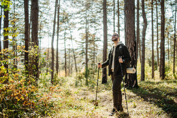 Young caucasian man hiking or trekking through the forest	