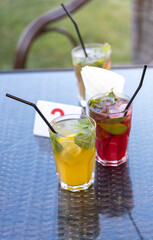 Three drinks with straws in them sit on a table