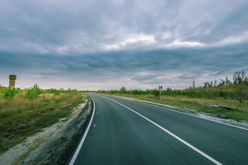 A long, empty road with a few trees in the background
