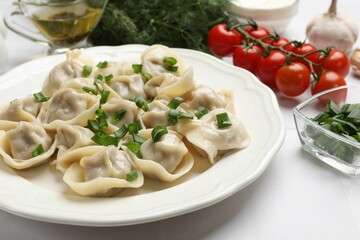 Delicious pelmeni with green onion served on white table, closeup