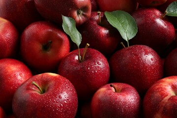 Fresh ripe red apples and green leaves as background, closeup