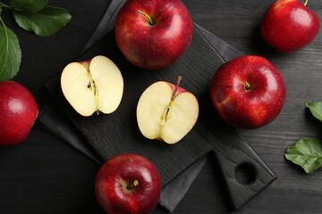 Whole and cut ripe red apples on black wooden table, flat lay
