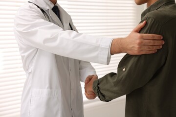 Doctor shaking hands with patient in hospital, closeup