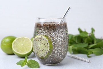 Glass of drink with chia seeds and lime on white table, closeup