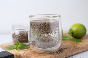 Glass of drink with chia seeds and lime on white table, closeup