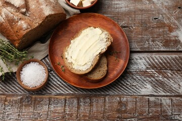 Fresh bread with butter, thyme and salt on wooden table, flat lay