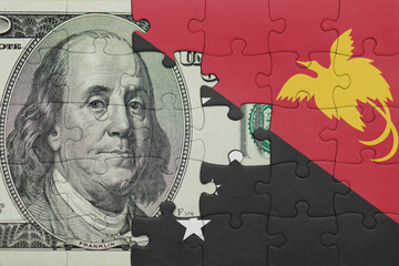 puzzle with the national flag of Papua New Guinea and the usa dollar money .finance concept
