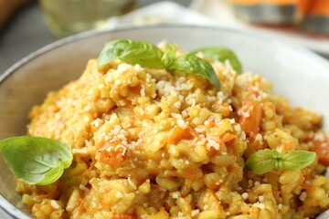 Delicious pumpkin risotto with basil on table, closeup
