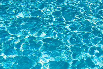 Water background. Blue water, ripples and highlights. Texture of water surface and tiled bottom.