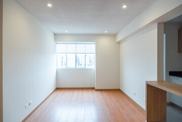 habitacion vacia de departamento con ventana hacia la calle paredes blancas y  piso de melamina color madera