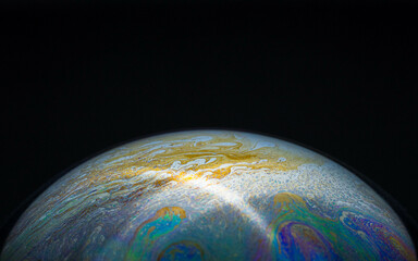 drawing of the earth with a bright flash ray on a hemisphere in a soap bubble on a black background, empty space for an inscription, ecology